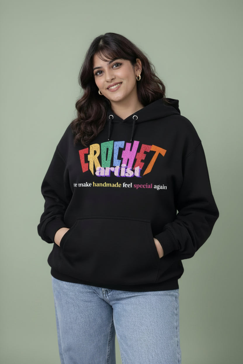Woman wearing a black hoodie with colorful text 'Crochet artist'  