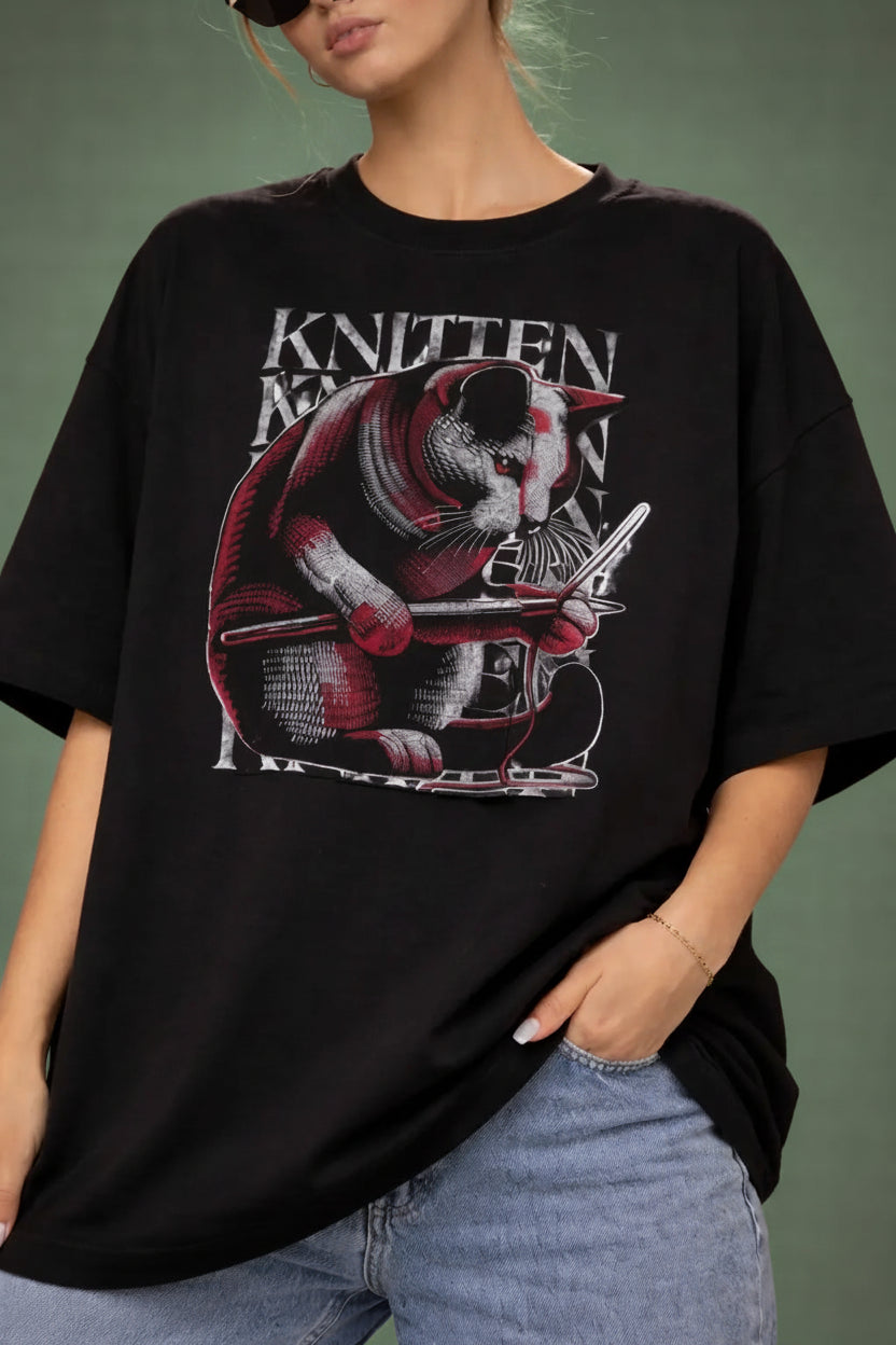 woman wearing a black oversized t-shirt with a graphic design of a cat and text.