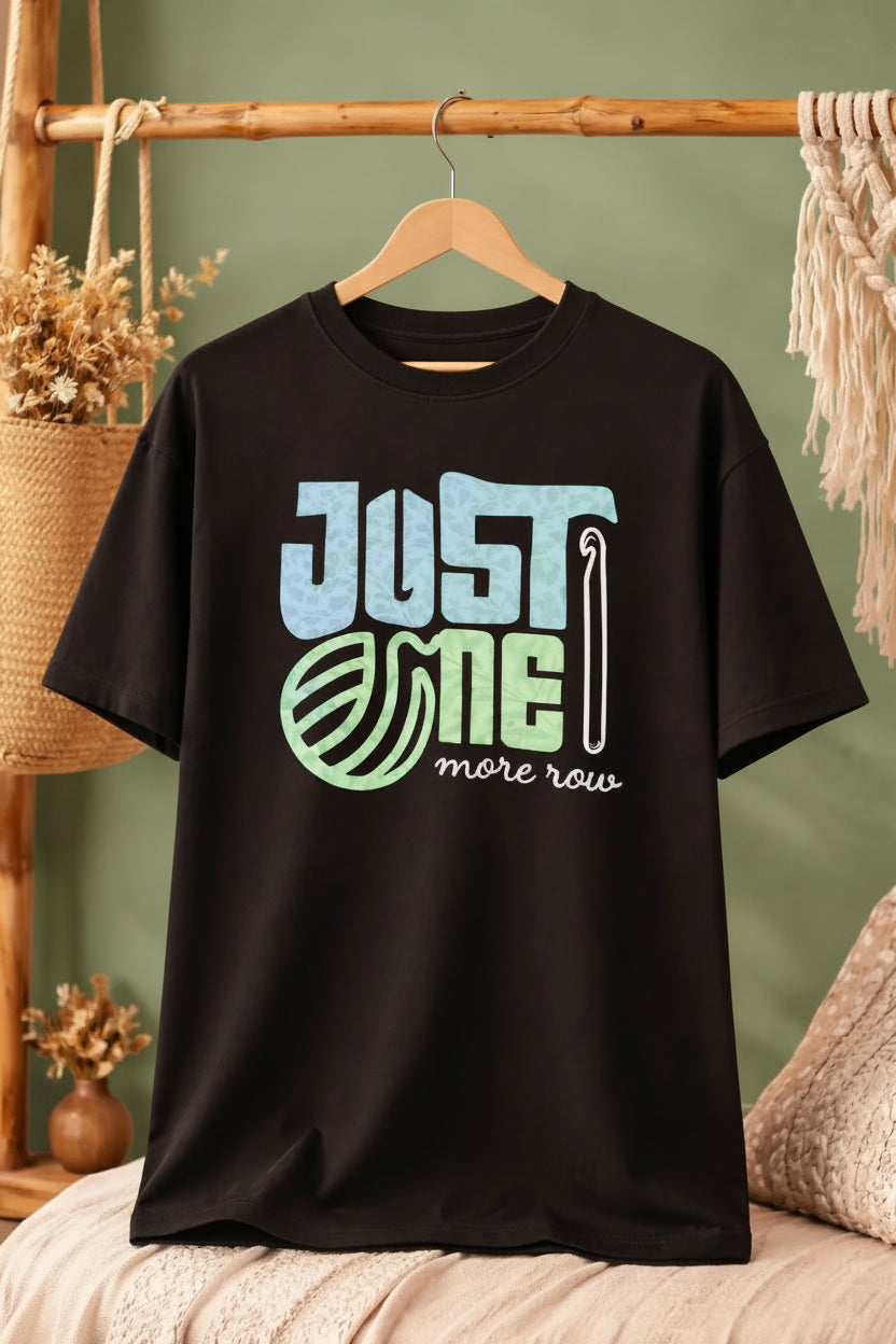 Black oversized t-shirt with 'Just One More Row' text on a wooden hanger  