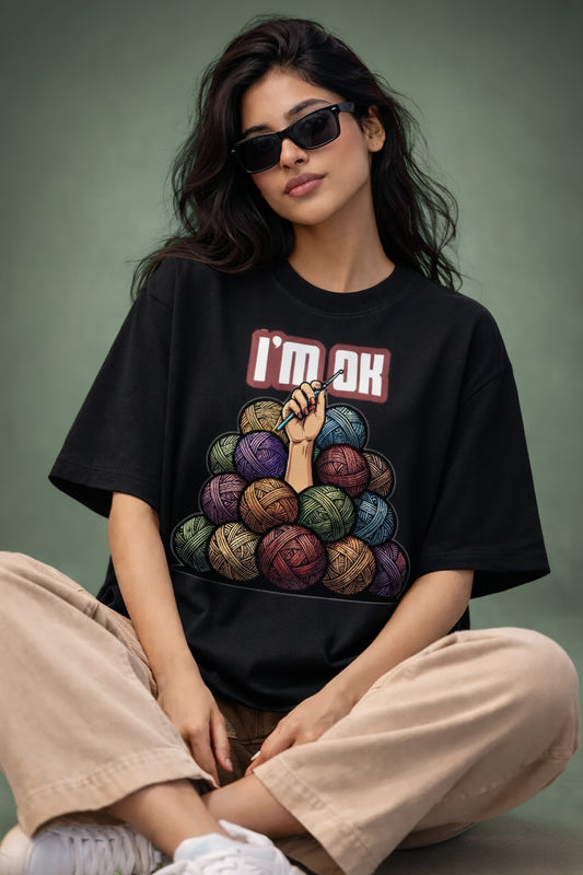Person wearing a black oversized t-shirt with colorful yarn design and text 
