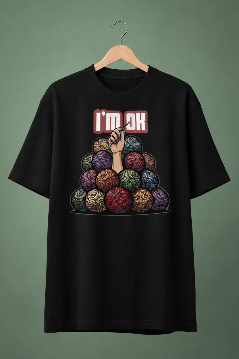 Black oversized  t-shirt with colorful yarn balls and 'I'm OK' text on hanger  